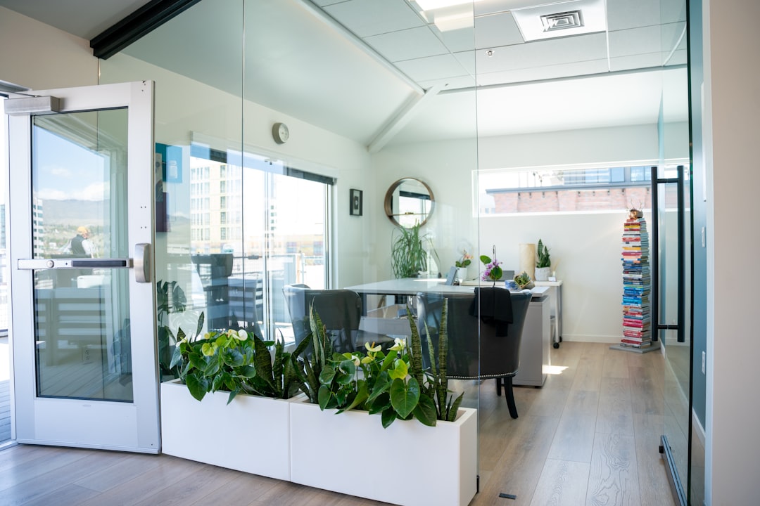 A diverse team of well-dressed real estate agents collaborates around a table in a bright, modern office, looking at plans on a large screen.